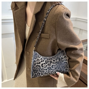 Detail view of the leopard print baguette bag on a model wearing a brown blazer