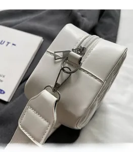 Gros plan d'un sac à main en cuir blanc avec crochets argentés et bandoulière large détail