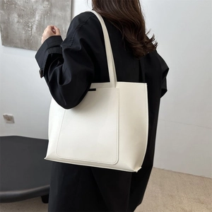 Side view of large beige tote bag worn by model showing minimalist style and texture
