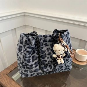 Borsa tote in peluche leopardata con tracolla a catena e ciondolo su tavolo in legno