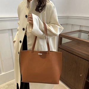 Detailed view of caramel tote bag with silver metal buckle and side pocket on shoulder strap