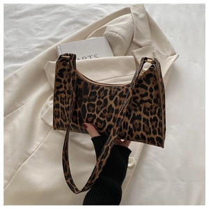 Detail shot of leopard print baguette bag with gold hardware on white background