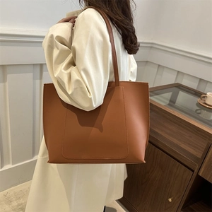 Detailed view of brown leather tote bag featuring a large pocket and minimalist straps