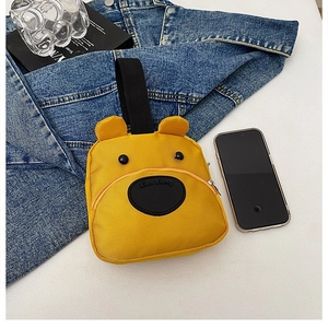Close-up of yellow bear-shaped nylon mini bag with carry handle on denim background