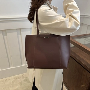 Detail of dark brown leather tote bag with rectangular stitching and silver buckle accent