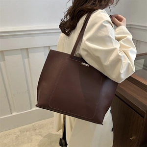 Detailed close-up of a deep brown minimalist leather tote bag with silver hardware detail