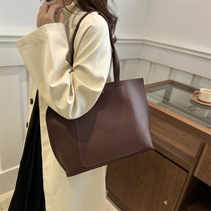Detailed close-up of dark brown leather tote bag showing fine stitching and pocket texture