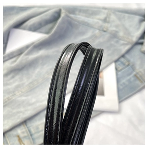 Détail de bretelles en cuir verni noir brillant avec coutures fines et texture micro-ridée