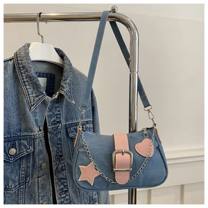 Détail du sac bandoulière en denim bleu avec touches de cuir rose et breloque étoile
