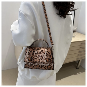 Model trägt Leopardenmuster-Schultertasche mit goldener Hardware in Minimal-Interieur