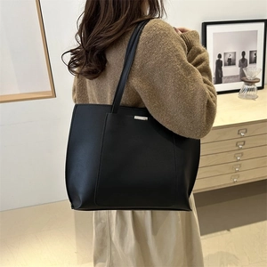 Detailed view of a black tote bag on a model showing large capacity and matte finish
