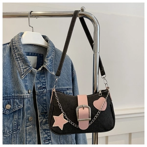 Détail de patchs cœur et étoile roses sur sac en jean noir avec chaîne argent