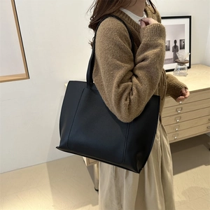 Minimalist black leather tote bag shown on model for stylish daily commuting wear