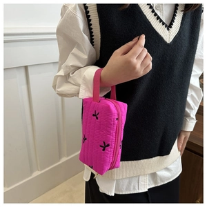 Detail of rose red quilted pouch with butterfly embroidery and pink wrist strap