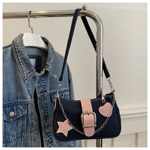 Détail du sac d'épaule en denim bleu avec touches de cuir rose et chaîne argentée