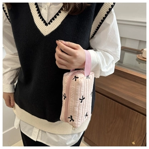 Détail de la trousse de maquillage rose matelassée avec broderie papillon noire