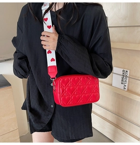 Vue détaillée du sac bandoulière rouge matelassé cœur avec large sangle à motifs