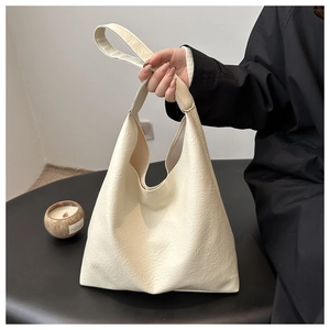 Detailed view of cream textured tote bag being held, showing large capacity and soft faux leather