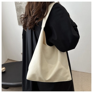 Detailed view of cream white hobo tote bag texture and draped shape on a model
