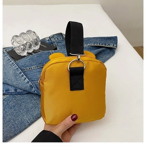 Detail of yellow nylon kid backpack showing black webbing handle and silver metal D-ring