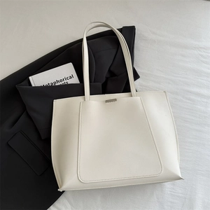 Close-up of cream faux leather tote bag with lychee texture on white fabric
