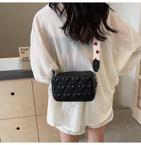 Détail du sac à bandoulière matelassé cœur noir avec sangle imprimée cœurs rouges