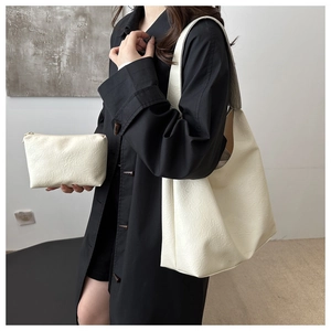 Detail view of cream white tote bag and matching pouch showing textured leather grain