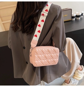 Détail du sac photo rose à cœurs matelassés avec bandoulière large à motifs cœurs