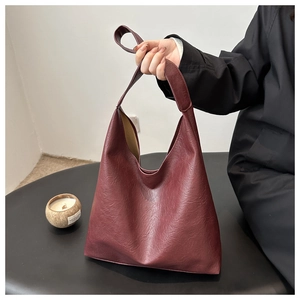 Detail view of burgundy leather tote showing lychee texture and sturdy integrated wide strap