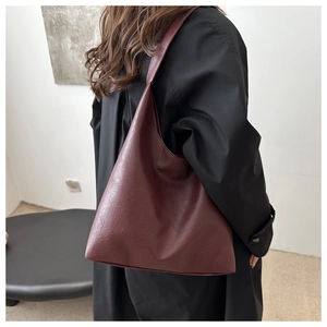 Detail view of large burgundy hobo bag in soft faux leather shown on a model's shoulder