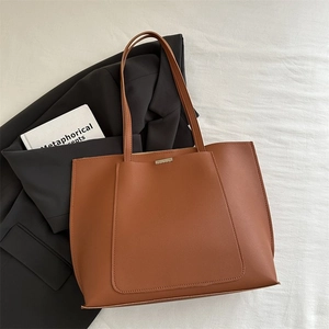 Detail view of brown leather tote bag with metal bar buckle on white textured background