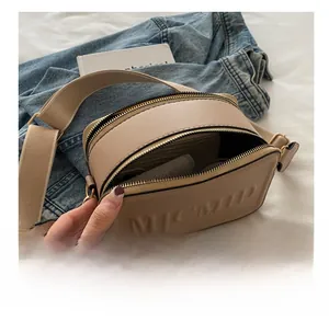 Detailansicht der Doppelreißverschlussfächer und breiter Schultergurt der beige Tasche