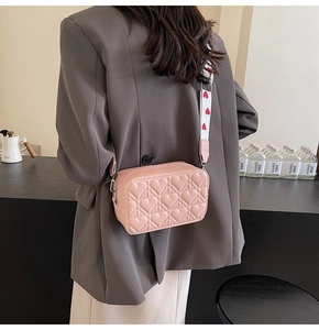 Détail du sac bandoulière rose avec matelassage en cœur et large sangle imprimée