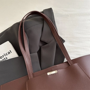 Detail shot of a dark brown leather tote bag with fine stitching and golden buckle