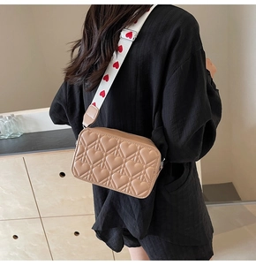 Détail du sac bandoulière kaki clair avec matelassage cœur et sangle à cœurs rouges