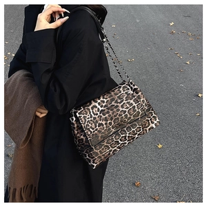 Détail d'un sac à bandoulière léopard avec chaîne argentée dans une scène d'automne