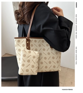 Detail of cream tote bag with floral monogram print and brown leather shoulder straps