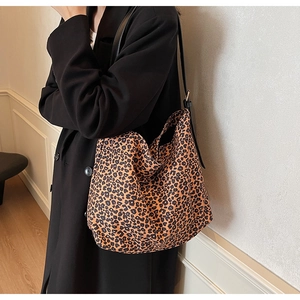 Détail du sac cabas en daim à motif léopard avec bandoulière noire réglable sur modèle