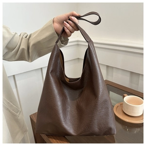 Detailed texture of dark brown vintage PU leather tote bag in a lifestyle home setting
