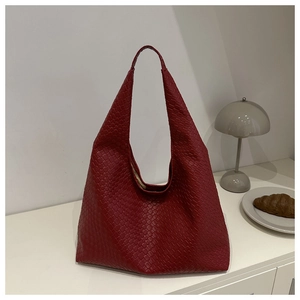 Détail de la texture en cuir tressé bordeaux d'un sac hobo minimaliste spacieux