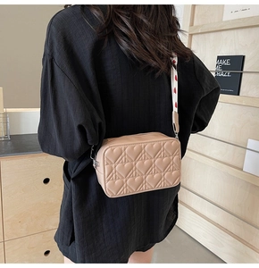 Détail du motif cœur matelassé sur le sac bandoulière carré beige à sangle