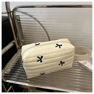 Vue détaillée de la trousse de maquillage matelassée crème avec broderie papillon noire