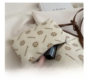 Close-up of a cream textured leather mini pouch with logo print and lipstick inside