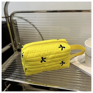 Vue détaillée d'une trousse à maquillage jaune matelassée avec broderie papillon et dragonne