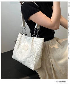 Detailed macro view of white woven texture tote bag with stylish silver metal chain straps