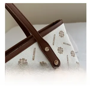 Close-up of white lychee texture tote bag with brown monogram pattern and gold metal rivets