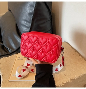 Détail du sac bandoulière rouge matelassé cœur avec large bandoulière à motifs