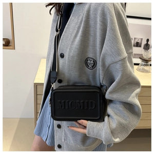 Detailaufnahme der schwarzen Umhängetasche mit MICMID-Logo und breitem Stoffgurt