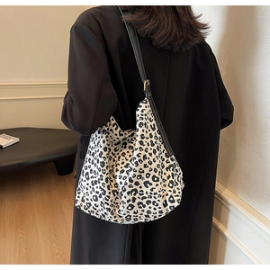Grand sac cabas léopard avec bandoulière en cuir noir porté par un mannequin