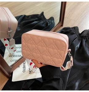 Détail du sac à bandoulière rose matelassé avec une large sangle imprimée de petits cœurs
